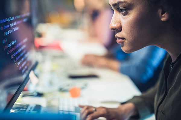 Person concentrated on a monitor screen showing code