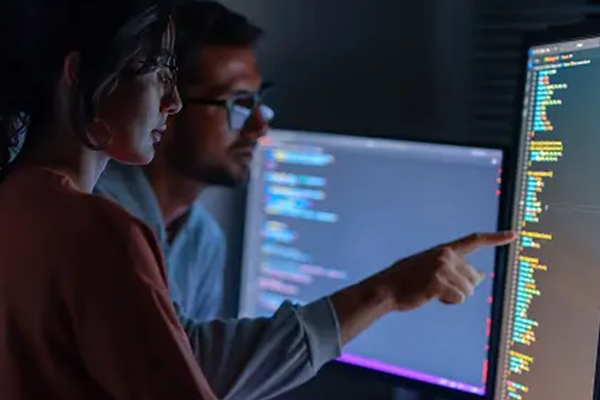 Person working at multiple screens with code