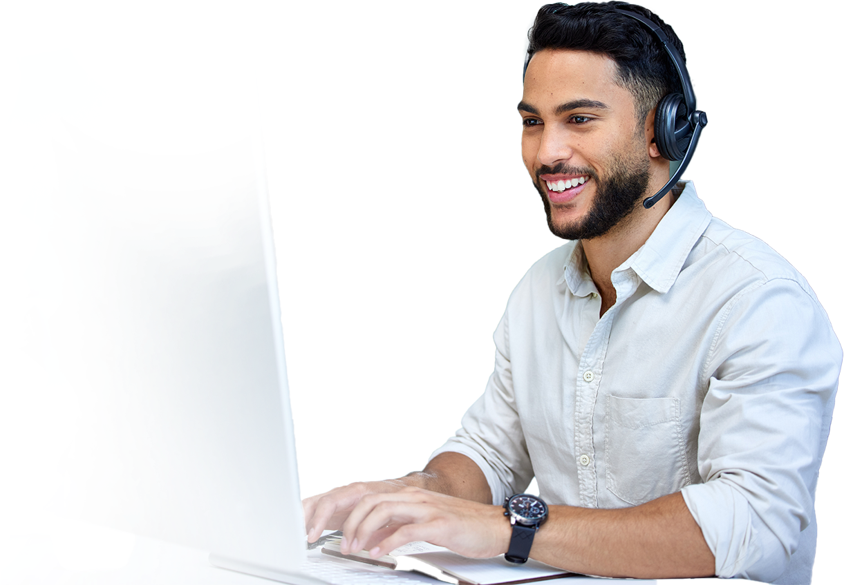 A smiling man in a white shirt and headset types on a laptop against a black background, conveying a professional and friendly customer service setting.